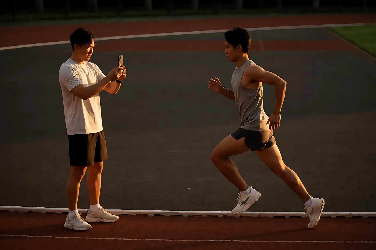 跑步姿势训练：教练用手机慢动作拍摄跑者侧面跑姿